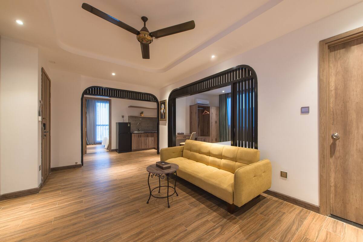 A modern living room with a yellow sofa, a small round table, and a ceiling fan.