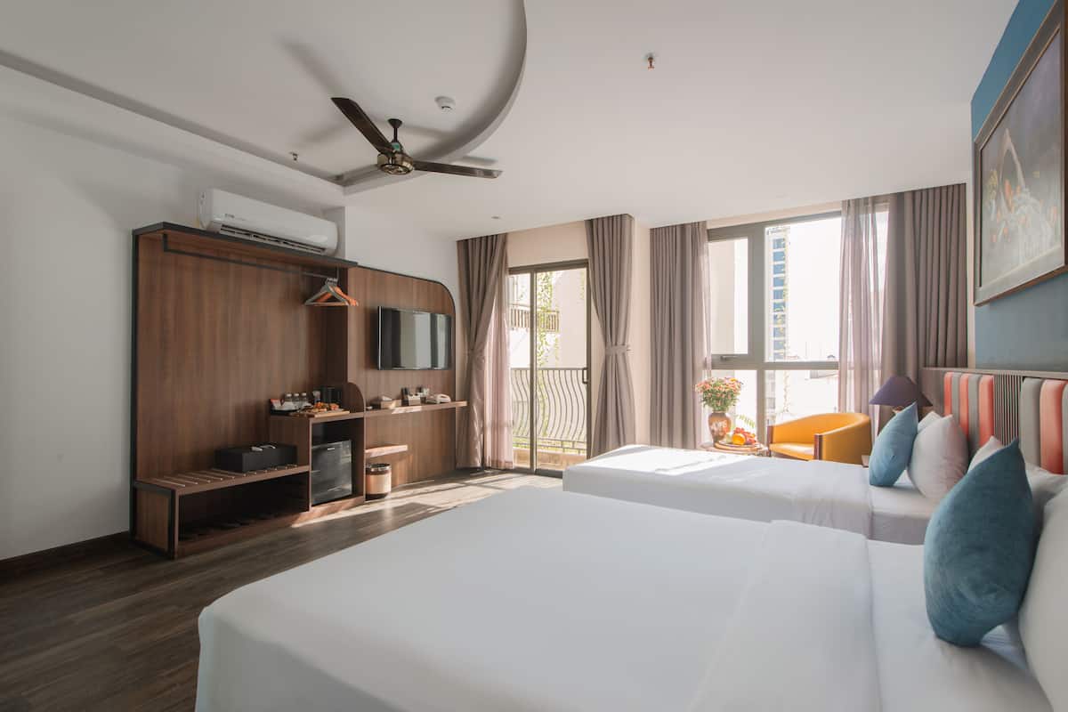 A hotel room with two beds, a wardrobe, a TV, and a balcony with curtains.