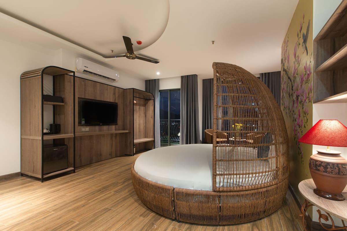 A modern bedroom with a circular bed, built-in TV, wardrobe, and a balcony with a view.