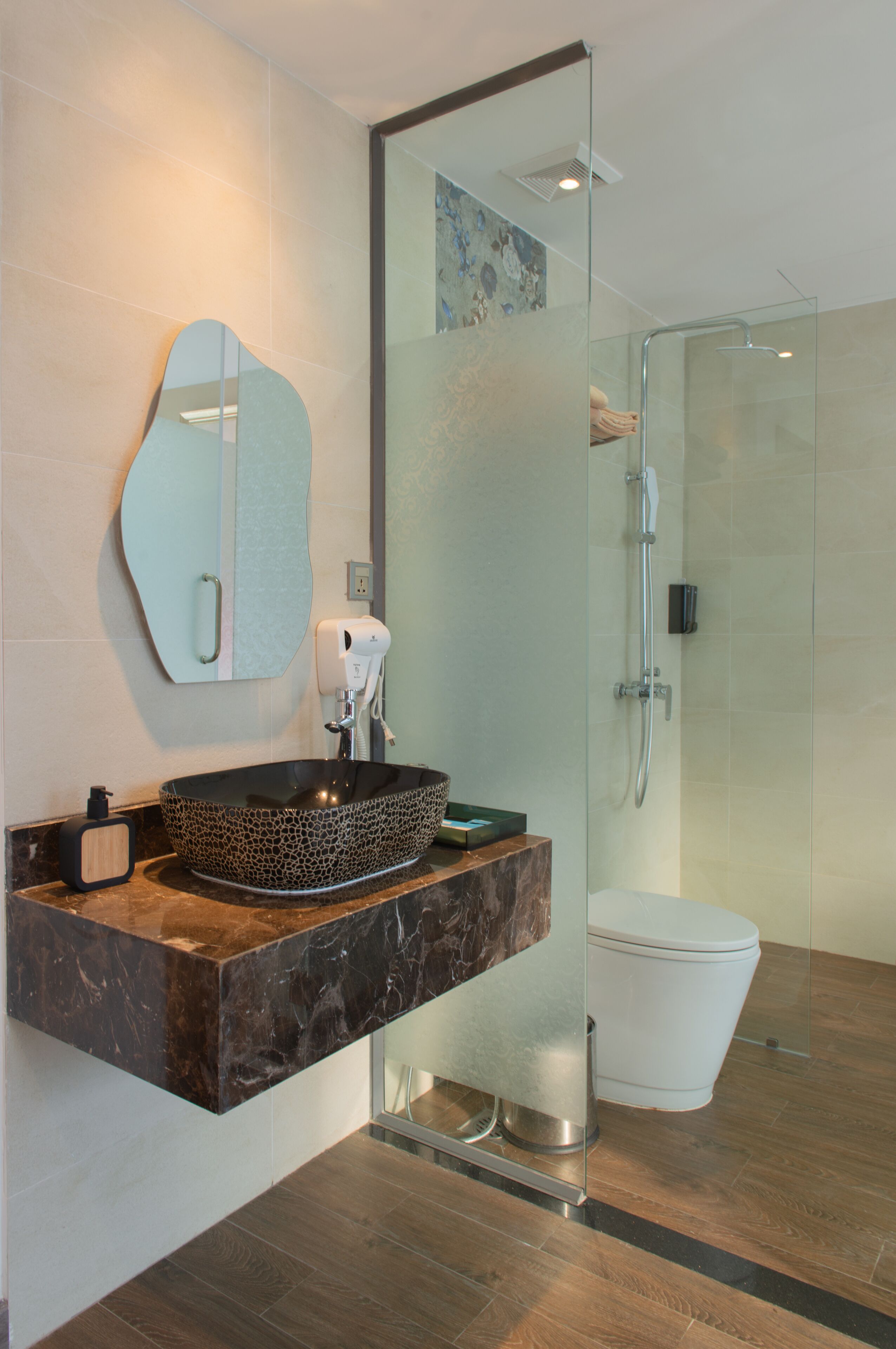 A modern bathroom with a glass-enclosed shower, a marble sink, and a toilet.