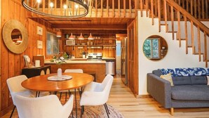 Een houten interieur met een eethoek, keuken en trap.