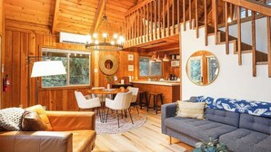 Een houten interieur met een eethoek, bank en een trap.