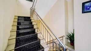 A staircase with black marble steps and a metal railing, leading to a landing with a potted plant. - Hotel O Wesly House (Medan)