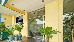 A building entrance with a glass door, potted plants, and a tiled floor. - Hotel O Wesly House (Medan)