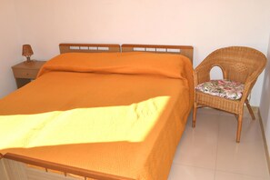 Restful retreat with a neatly made bed and a wicker chair for relaxation.