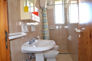 Bathroom features a sink, two toilets, and a shower with a geometric-patterned curtain.