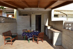 Enjoy a romantic meal for two in this charming outdoor dining area, complete with a beautifully set table and a kitchen nearby.