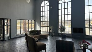 A spacious room with large windows, a fireplace, and comfortable seating. - Baymont by Wyndham Flint Airport North (Flint)