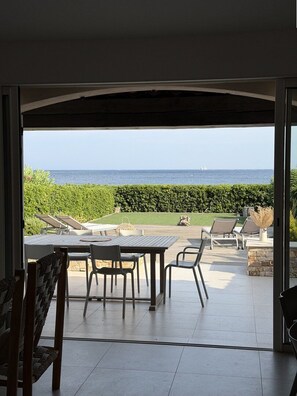 An open patio with a table and chairs, a view of the ocean, and a hedge in the background. - Mazet for 6 people, near the beach and town centre. Swimming pool in the residence (SAINTE MAXIME)