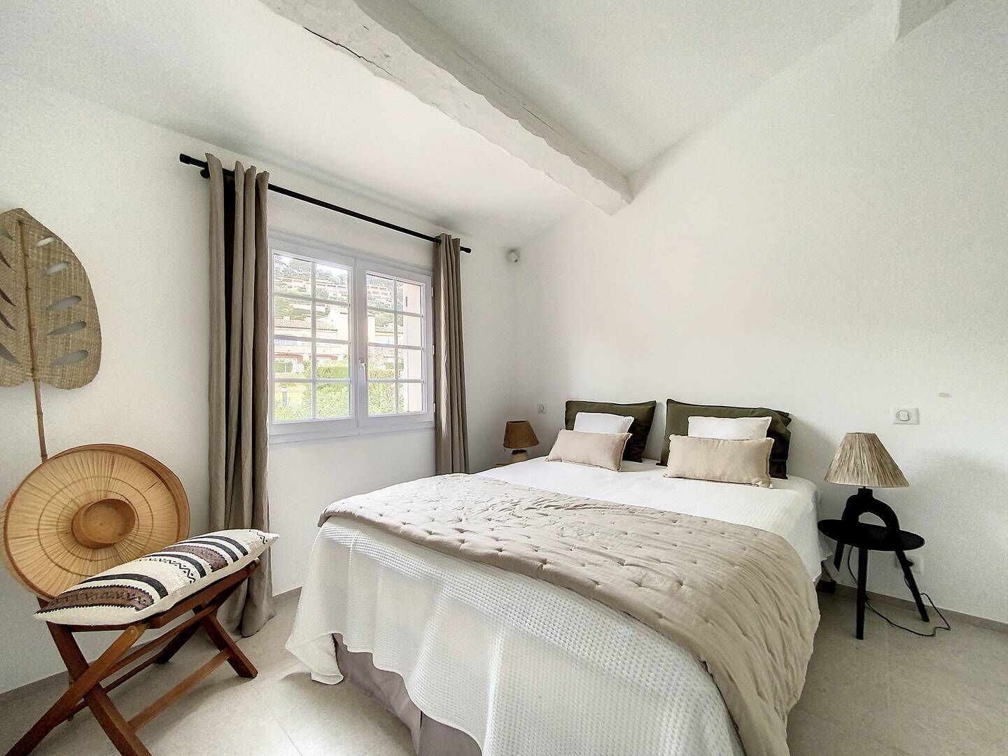 Un dormitorio con una cama, una silla, una lámpara y una ventana.