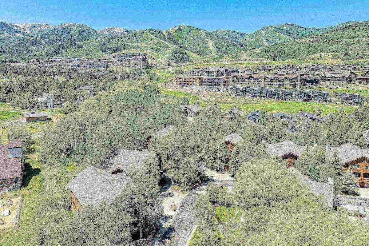 A resort area with multiple buildings, some with visible balconies, surrounded by dense trees and hills in the background.