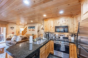 A kitchen with wooden cabinets, a stainless steel refrigerator, and a granite countertop.