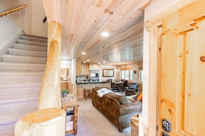 A wooden interior with a staircase, a sofa, a dining table, and a kitchen area.