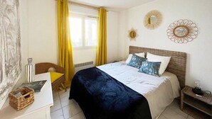 A bedroom with a bed, a desk, a chair, and a window with curtains. - Bel Appartement 3 Pièces Climatisé 400m des Plages (CAVALAIRE SUR MER)