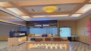 A modern kitchen area with a sign reading 'Cooking Station,' equipped with various appliances and a display of kitchenware.