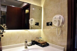 A bathroom with a marble wall, a mirror, a sink, a telephone, and a small wooden tray with toiletries.