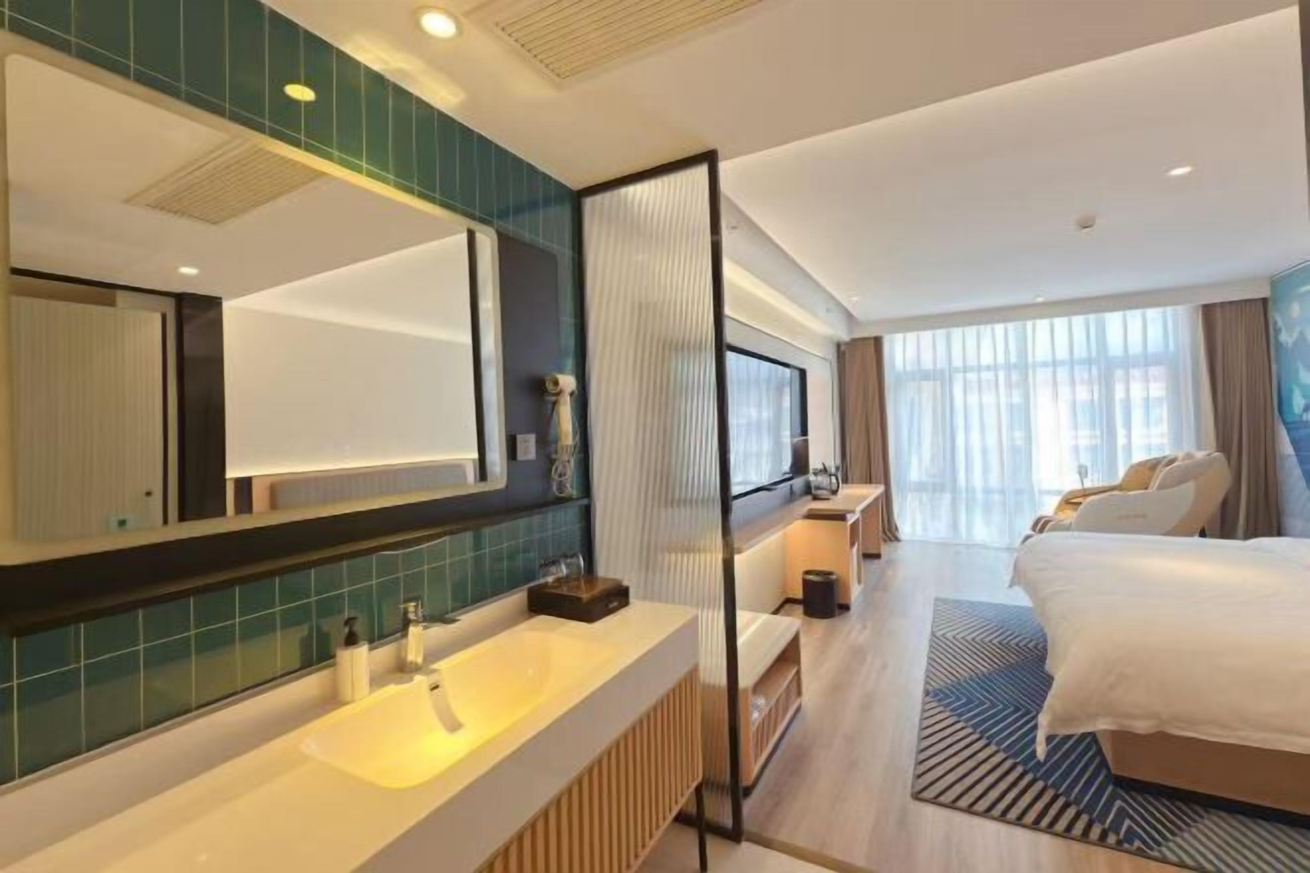Moderni hotellihuone, jossa on suuri sänky, tilava kylpyhuone, jossa on suuri peili, ja näkymä kaupunkiin.