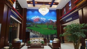 A lobby with a large mural, a chandelier, and a seating area with sofas and a coffee table.
