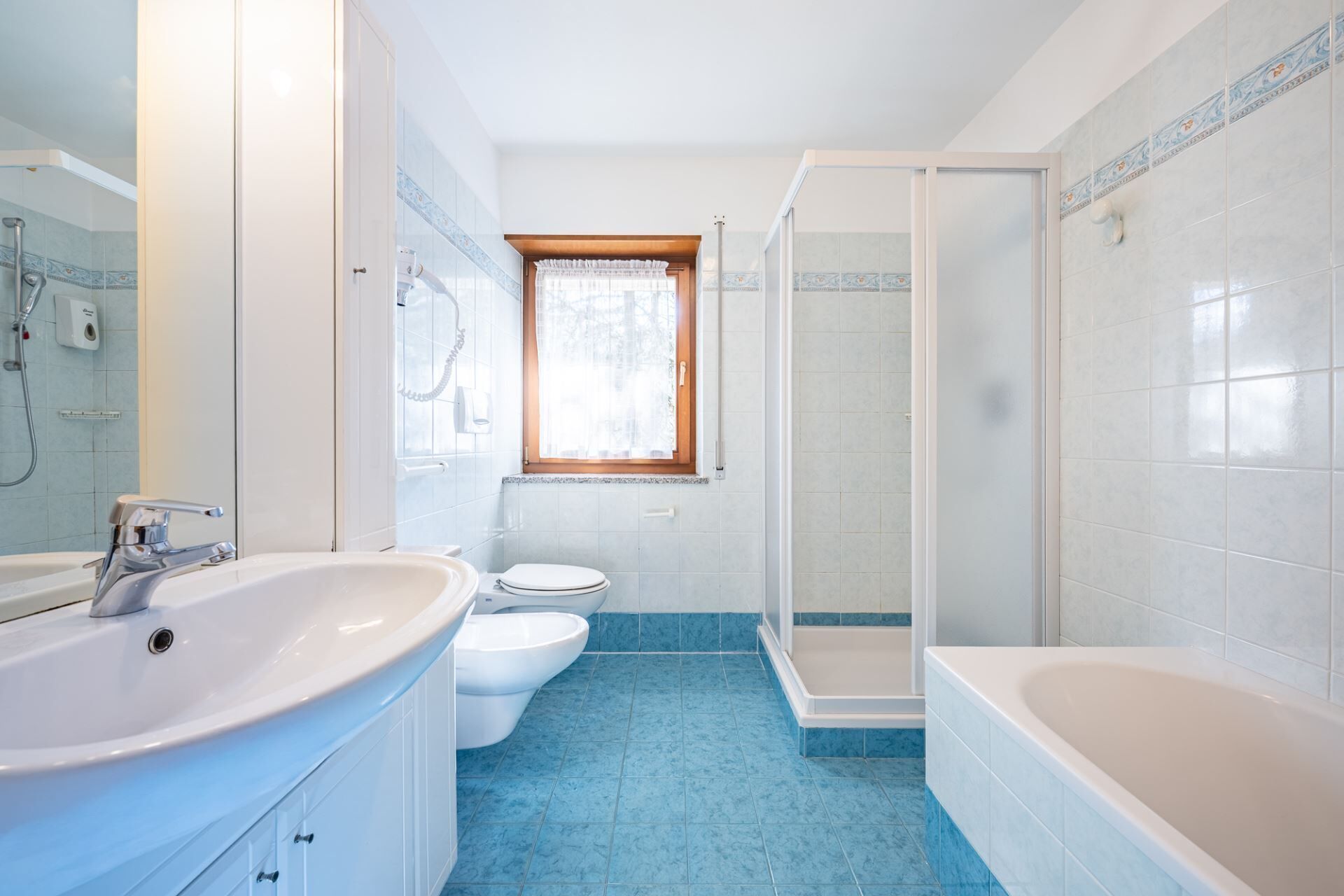 Een badkamer met een bad, douche, toilet en wastafel.