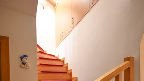 En trappa av trä med röda, matta klädda trappsteg, ett träräcke och en liten dekorativ detalj på väggen.