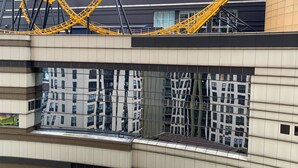 A modern building with a roller coaster structure above the entrance, large reflective windows, and a multi-story design. - Elegant Studio At Transpark Cibubur Apartment Near Shopping Mall (Bekasi)