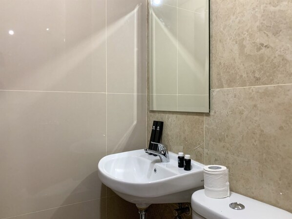 A bathroom with a white sink, a mirror, and a toilet.