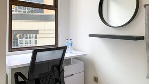 A modern office space with a desk, chair, and a large window overlooking a construction site. - Elegant Studio At Transpark Cibubur Apartment Near Shopping Mall (Bekasi)