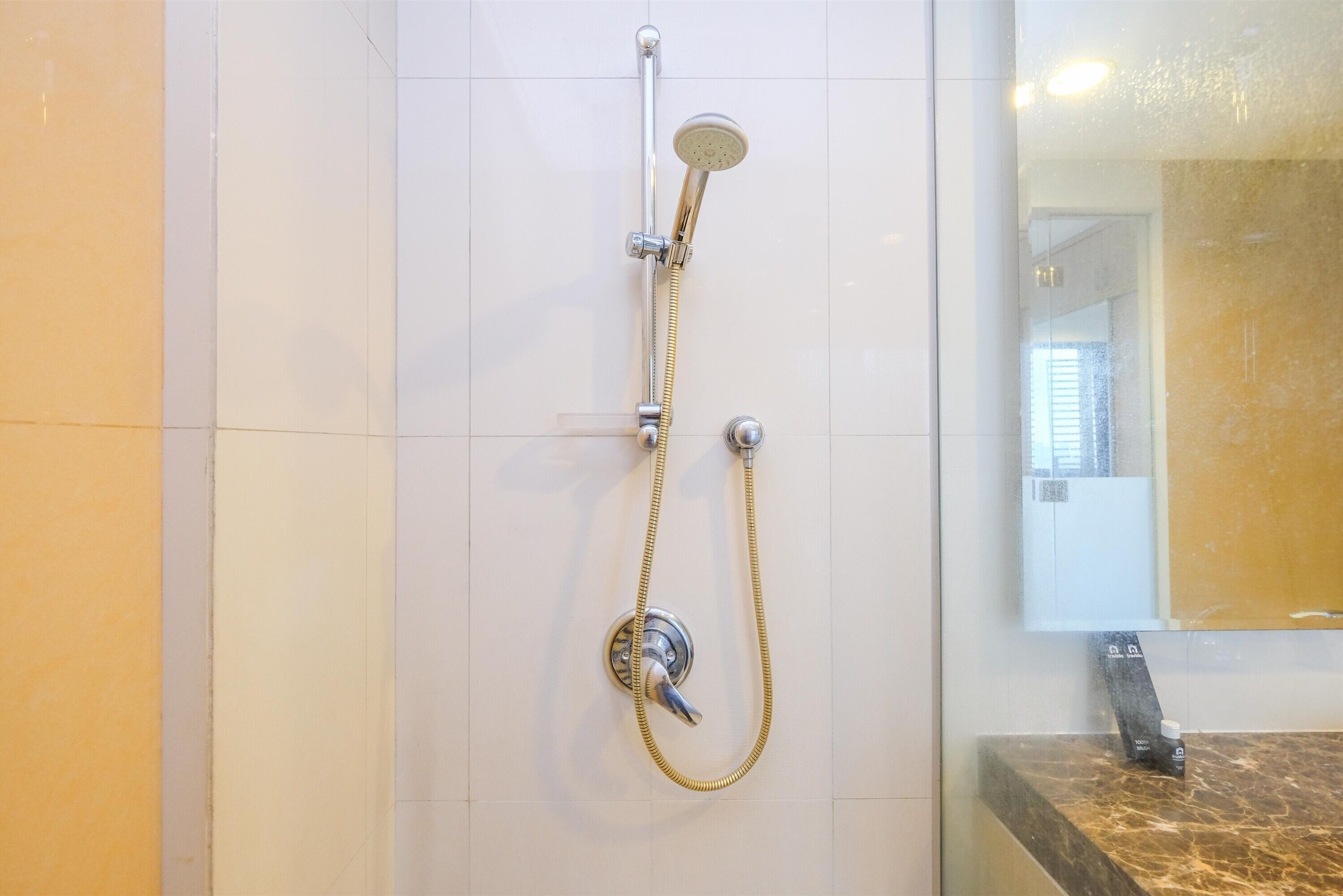 A bathroom with a shower, a mirror, and a marble countertop.
