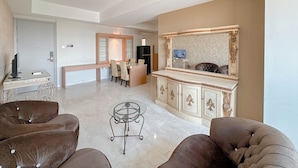 A spacious living area with a marble floor, a round glass coffee table, and two brown upholstered sofas. - Nice 3Br Connected To Mall At Grand Sungkono Lagoon Apartment (Surabaya)