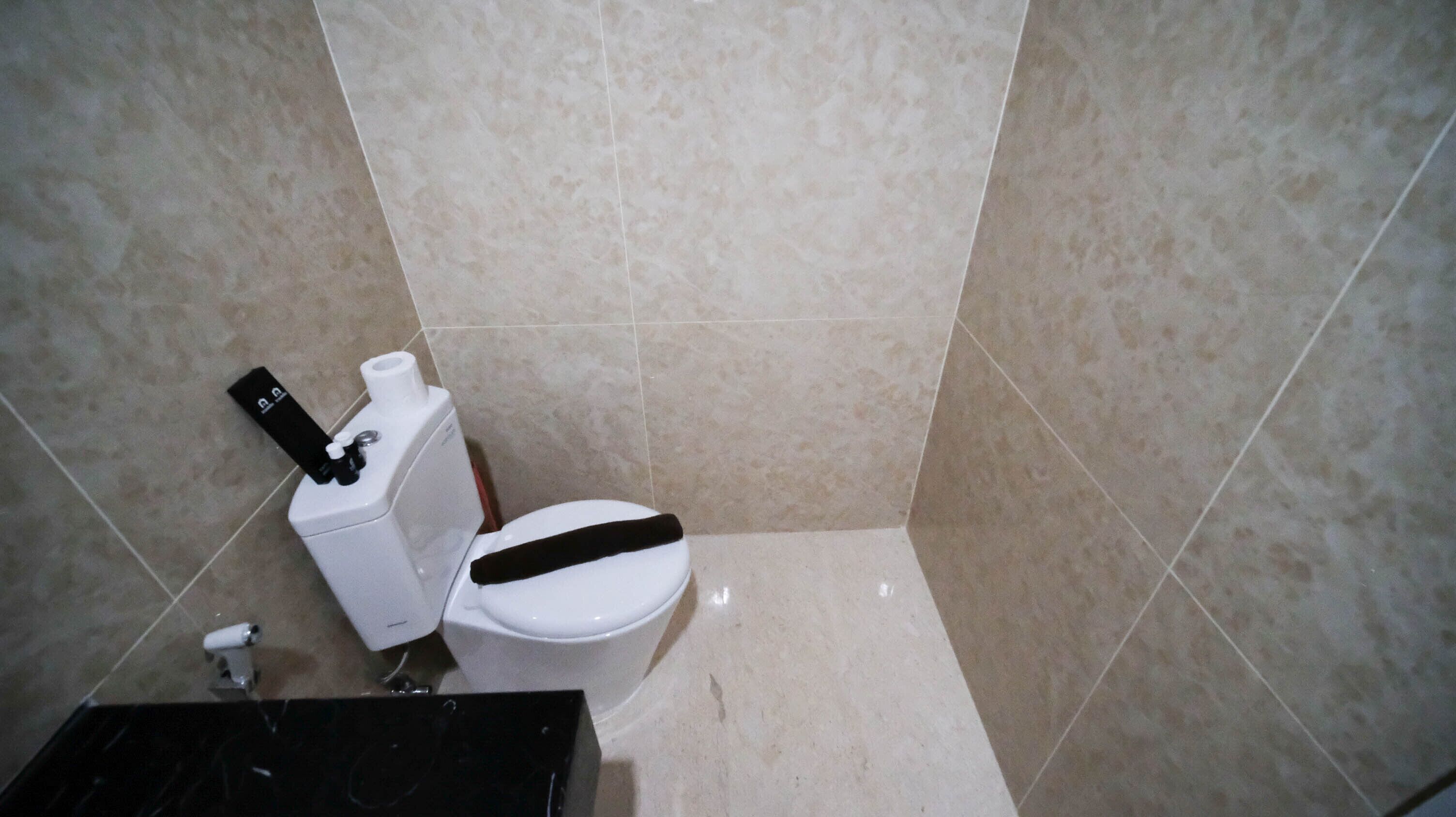 Une petite salle de bain comprenant des toilettes, un lavabo et un porte-rouleau de papier toilette.