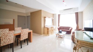 A modern living room with a dining area, a sofa, and a TV. - Nice 3Br Connected To Mall At Grand Sungkono Lagoon Apartment (Surabaya)