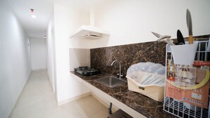 A compact kitchen with a marble countertop, a sink, and a dish rack. - Nice 3Br Connected To Mall At Grand Sungkono Lagoon Apartment (Surabaya)