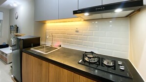 A modern kitchen with white cabinets, a black countertop, and a gas stove. - Simply Studio Room LRT City Jatibening Apartment (Bekasi)