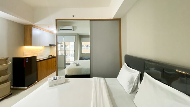 A hotel room with a bed, a desk, a chair, a sink, and a window. - Simply Studio Room LRT City Jatibening Apartment (Bekasi)