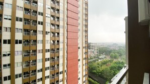 A high-rise building with multiple balconies and a view of a green landscape below. - Simply Studio Room LRT City Jatibening Apartment (Bekasi)