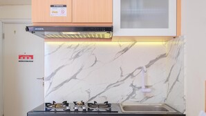 A kitchen with a gas stove, a stainless steel sink, and a marble backsplash.