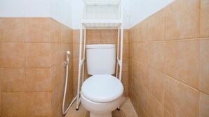 A small, enclosed bathroom with a toilet, a shower, and tiled walls.