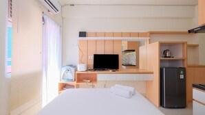 A hotel room with a bed, a TV, a refrigerator, a kettle, and a water dispenser.