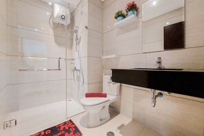 A modern bathroom with a glass-enclosed shower, a white toilet, a black sink, and a mirror above the sink. - Comfort Designed 1Br At Brooklyn Alam Sutera Apartment (South Tangerang)