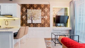A modern living room with a sofa, a TV, and a dining area with a table and chairs. - Comfort Designed 1Br At Brooklyn Alam Sutera Apartment (South Tangerang)