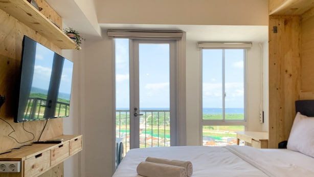 Ein Schlafzimmer mit einem Bett, einem an einer Holzwand montierten Fernseher und einem Balkon mit Blick.