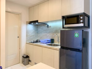 Compact kitchen area with a refrigerator, microwave, gas stove, and sink.