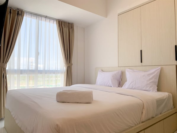 Relax in a spacious room with a large bed, minimalist design, and a functional layout.