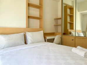 Comfortable room with a neatly made bed, desk, and shelving units.