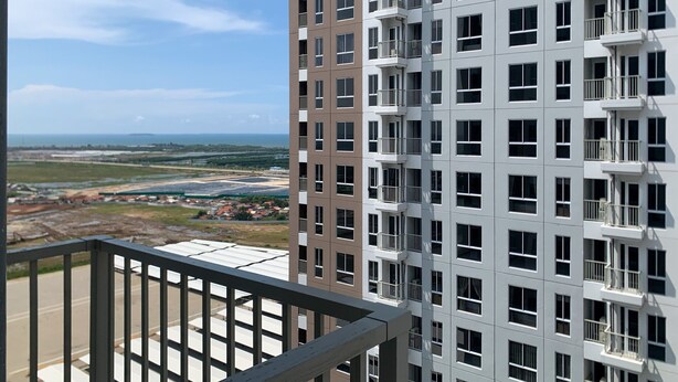 A high-rise residential building with multiple balconies, a clear view of the surrounding landscape, and a distant body of water. - Relaxing 2Br At 35Th Floor Tokyo Riverside Pik 2 Apartment (Teluknaga)