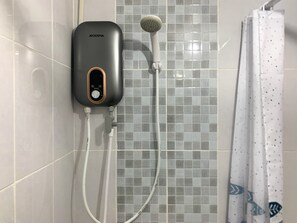 A modern bathroom with a grey tiled wall, a black water heater, a handheld showerhead, and a white curtain with a fish pattern.