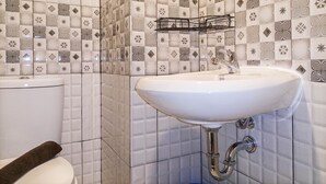 A bathroom with a white sink, a toilet, and a tiled wall with geometric patterns.
