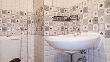A bathroom with a white sink, a toilet, and a tiled wall with geometric patterns.