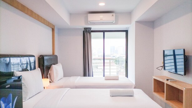 A hotel room with two beds, a TV, and a city view.