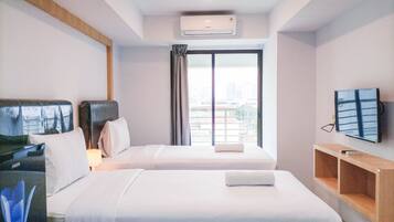 A hotel room with two beds, a TV, and a city view.